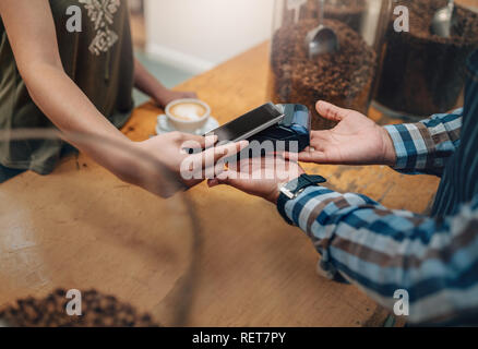 Customer making wireless or contactless payment using credit card using NFC technology. focus on hands Stock Photo