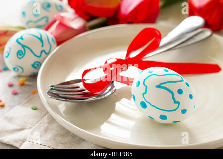 Easter table setting with tulips flowers, Easter eggs and cutlery close-up. Holidays background. Stock Photo