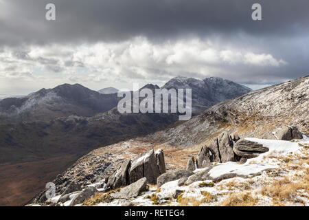 A snow capped Snowdon sit under dark clouds. Viewed from Gylder Fach, Snowdonia National Park Stock Photo