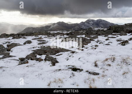 A snow capped Snowdon sit under dark clouds. Viewed from Gylder Fach, Snowdonia National Park Stock Photo