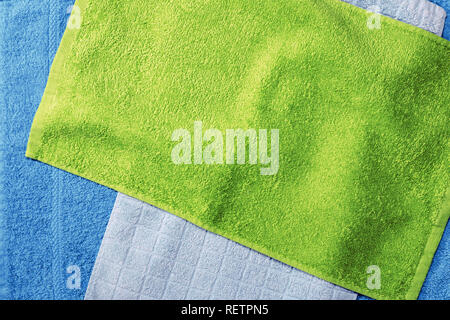 Heap of multi-colored towels on a beige wooden background Stock Photo