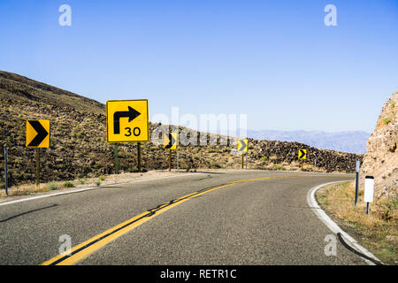 Steep right turn on a winding road; posted sign showing a 30 mph recommended speed; California Stock Photo