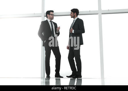 two businessmen standing near a large office window Stock Photo