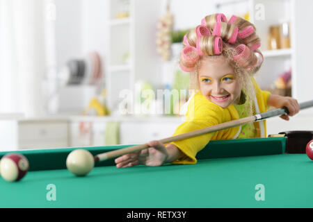 Portrait of cute little girl playing billiard Stock Photo
