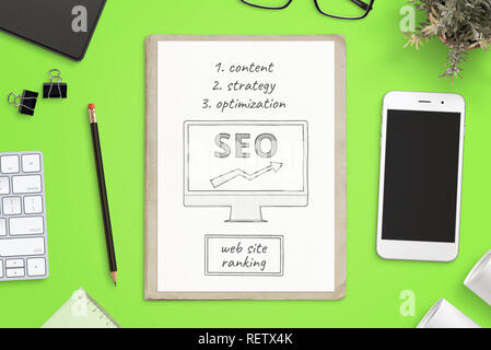 Search engine optimization goals sketch on paper and smart phone mockup beside on green office desk. SEO concept composition. Top view. Stock Photo