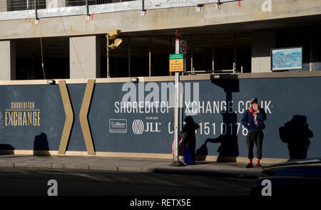 People waiting at a bus stop by a new luxury housing development in Shoreditch,London,England,UK Stock Photo