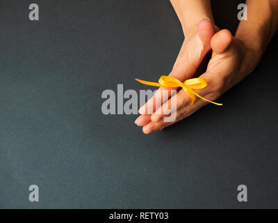 Hands of a couple in love. Fingers tied by a yellow bow Stock Photo