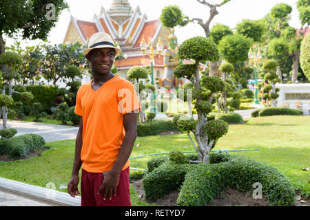 Young happy black African tourist man smiling at Wat Arun Stock Photo