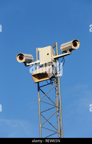 Low angel view of two outdoor surveillance cameras against a blue sky. Stock Photo