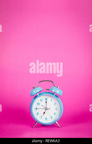 Beautiful retro blue pastel alarm clock on a vibrant pink background Stock Photo