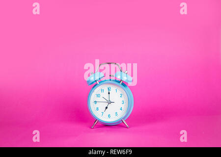 Beautiful retro blue pastel alarm clock on a vibrant pink background Stock Photo