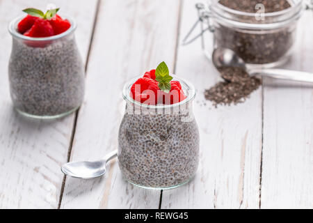 Closeup of served glass jars filled with sweet pudding of chia seeds and garnished with fresh raspberry and mint Stock Photo