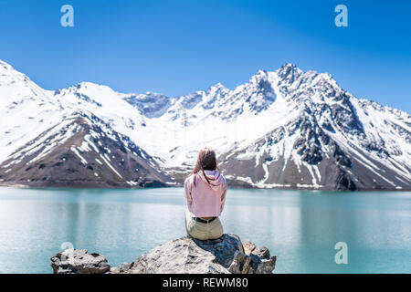 Girl looking at the amazing mountain views of the turquoise waters from the 'Embalse del Yeso' (Cast Lake) inside Cajon del Maipo at Andes Mountains Stock Photo
