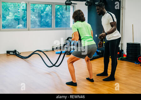 Man with battle rope in functional training fitness gym Stock Photo