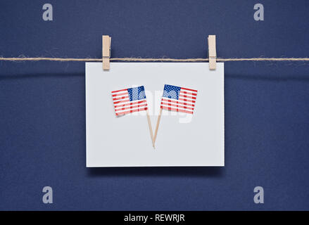 Two Miniature flags of America USA on white postcard on blue background hanging with clothespins. Greeting card for celebration of President's Day in  Stock Photo