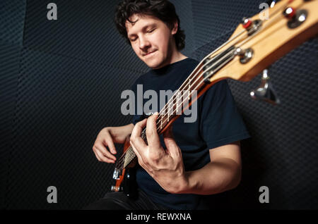 Handsome rock bass guitarist practicing in sound studio. Stock Photo