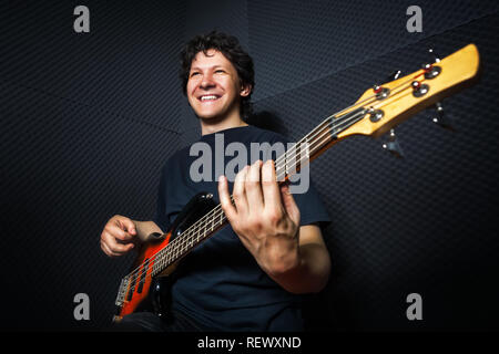 Handsome rock bass guitarist practicing in sound studio. Stock Photo