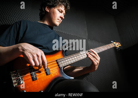 Handsome rock bass guitarist practicing in sound studio. Stock Photo