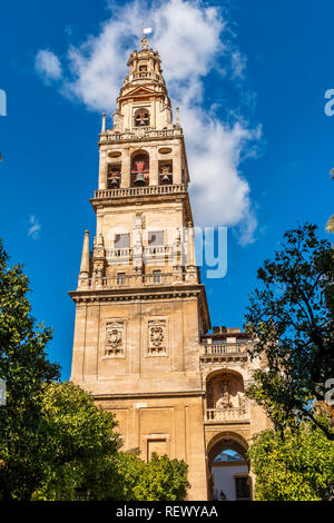 From below shot of high old ornamental bell tower of the Mezquita (Mosque Cathedral) under blue sky in Cordoba, Spain Stock Photo