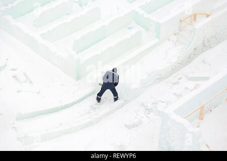 Worker with a chainsaw in hand at the assembly site of the ice town Stock Photo