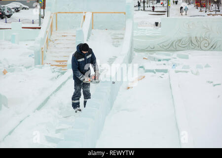 Worker with a chainsaw in hand at the assembly site of the ice town Stock Photo