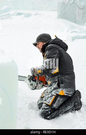 Worker with a chainsaw in hand at the assembly site of the ice town Stock Photo