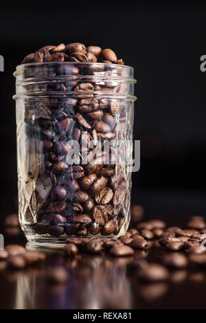 Coffee beans in a glass jar and spilled on the table Stock Photo