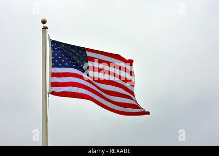 American Flag waving on pole against sky Stock Photo