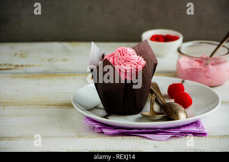 Pink cupcake on plate. Frosting cupcake decorated with raspberry and cream cheese Stock Photo