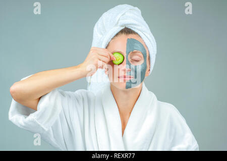 Spa Clay Mask. Beautiful young woman with clay facial mask with cucumbers on eyes. Skincare and beauty Concept. Stock Photo