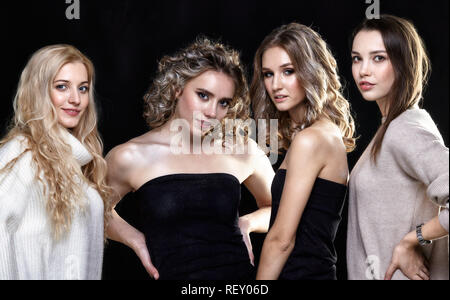 Group portrait of four women on black background.Two female models and two makeup artists. Stock Photo