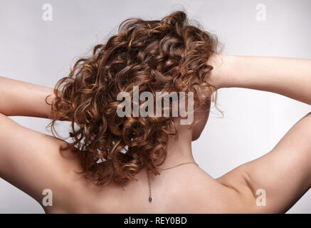Woman from backside on gray background. Female with curly hair.