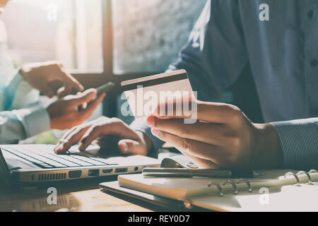 Businessman holding credit card and using laptop. Making payment while online shopping. E-commerce and modern technology concept Stock Photo