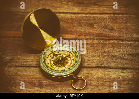An old compass on a brown wooden table Stock Photo