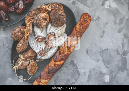 Dried persimmon, figs and melon on a black plate on a wooden background. Close-up. Copy space. Selective focus Stock Photo