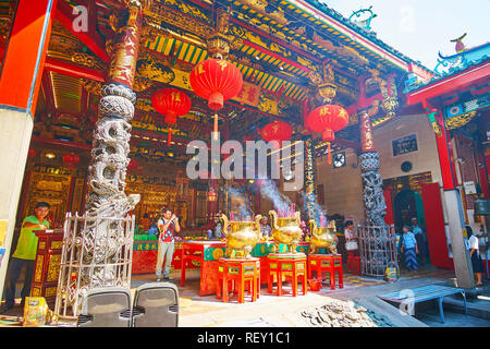 YANGON, MYANMAR - FEBRUARY 17, 2018: The inner yard of Kheng Hock Keong Temple with carved wooden columns, large red lanterns and the fuming incense s Stock Photo