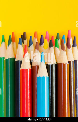 An assortment of colour pencils on yellow background. School supplies, creativity concept Stock Photo