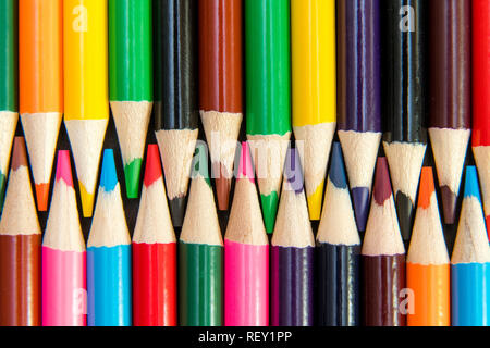 Close-up of colored pencils arranged in interlock pattern on white background Stock Photo