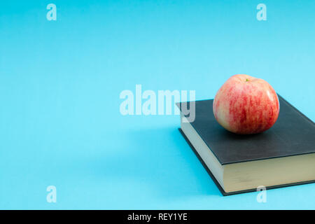 Hard cover book with an red apple on top blue background. Education concept Stock Photo