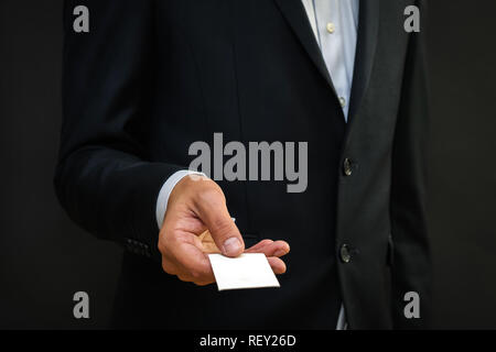 Young man hands out blank business card from the pocket of his suit. Discussion talking deal concept Stock Photo