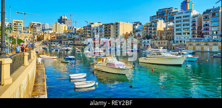 ST JULIANS, MALTA - JUNE 20, 2018: Panorama of Spinola Bay harbour with numerous fishing boats, white dinghies and traditional Maltese luzzu vessels,  Stock Photo