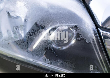 Car headlights covered in frost on early autumn morning.  Dropping temperature approaching winter, ice crystals Stock Photo