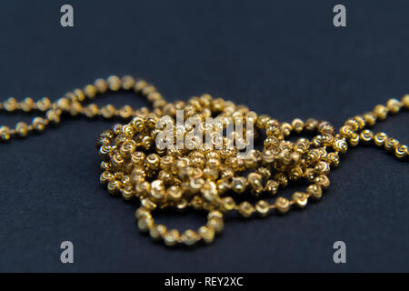 Gold necklace isolated on black background, macro closeup showing yellow golden chain links detail Stock Photo