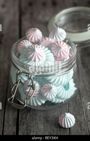 Light Pink and blue meringues in glass jar on dark background, vertical composition Stock Photo
