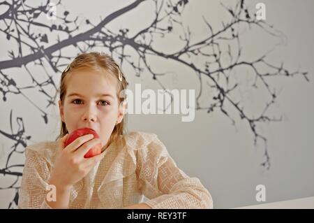 White Caucasian girl (child, kid) eat a red apple. Copy text Stock Photo