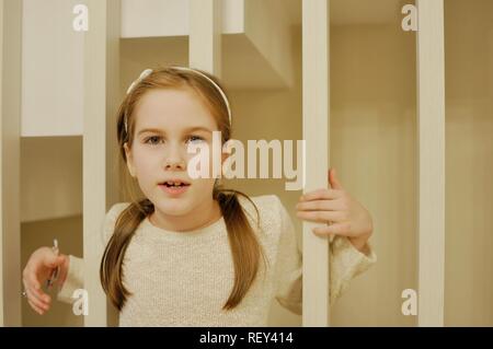 Portrait of an happy surprised blonde white Caucasian 9 years old girl. The child has long hair and blue eyes. Front view Stock Photo