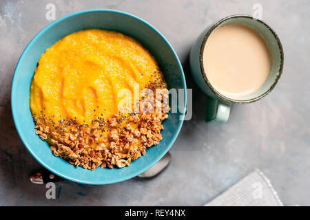 Top view of yellow smoothie bowl with granola in blue plate Stock Photo
