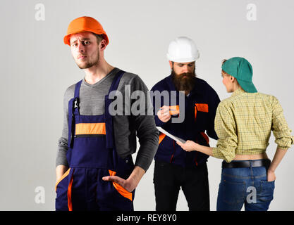 Planning a new construction. Hard worker rest while team members discussing construction project in background. Construction worker in work wear. Building engineer or builder and his team at work Stock Photo