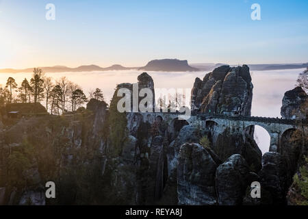 Landscape in the National Park Sächsische Schweiz with rock formations, Bastei bridge and trees, fog in the river Elbe valley at sunrise Stock Photo