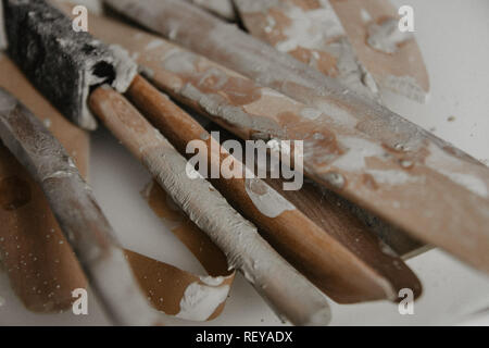Set of dirty art and craft sculpting tools on wooden table in pottery workshop Stock Photo